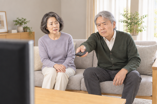 テレビの音量を上げようとして会話が途切れるシニア夫婦